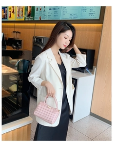Pink Boston bag with geometric pattern and golden bow clasp styled with chic attire