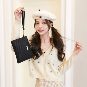 Detailed view of a black quilted wristlet bag with V-shaped stitching and gold logo plate