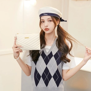 Detail of white quilted envelope clutch with gold metal buckle and leather wristlet