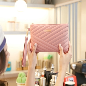 Close-up of pink quilted envelope clutch bag with gold zipper and detachable wrist strap