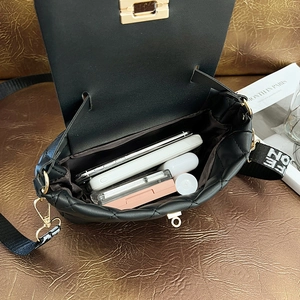 Spacious interior of black quilted crossbody bag with daily essentials and logo strap