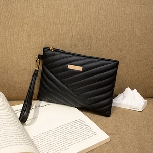 Detail of black quilted leather envelope clutch with gold metal plate and wrist strap
