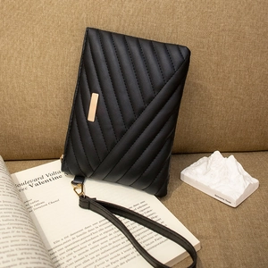 Close-up of black envelope clutch bag featuring geometric quilting and gold metal hardware