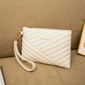 Detail of cream quilted clutch featuring gold hardware and removable wristlet strap