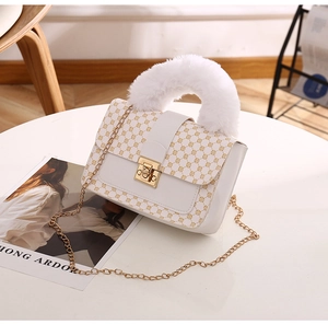 Detail of white square bag with plush handle, gold chain strap, and geometric pattern