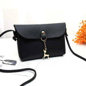 Mini black PU leather crossbody bag with golden deer pendant on white surface