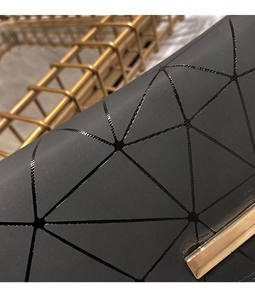 Detail der schwarzen Brieftasche mit geometrischem Muster und goldener Metallschließe