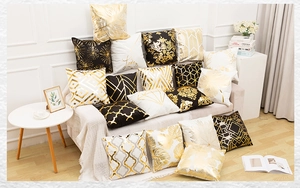 Detalle de cojines de lujo en negro, blanco y dorado con patrones geométricos y hojas
