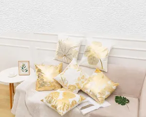 Dettaglio di federe quadrate in peluche bianco con motivi a foglia d'oro metallizzato