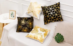 Dettaglio di cuscini quadrati con lamina d'oro e motivi geometrici e di foglie su divano
