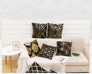 Detail of black velvet pillow with gold foil patterns on a modern white sofa