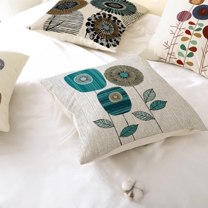 Nordic floral polyester cushion covers in blue and mustard on a clean white bed