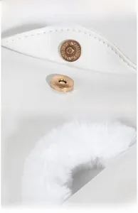 Detail of white faux fur handle and polished gold magnetic closure on a square handbag