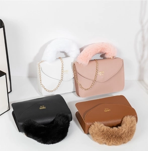 Detail view of four textured leather crossbody bags with plush handles and gold chains
