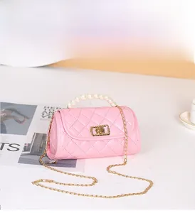 Detail of pink quilted handbag with pearl top handle and golden chain strap
