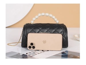 Mini black quilted bag with pearl handle and gold chain compared to smartphone size