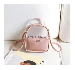 Close-up of pink translucent mini backpack with Little Beauty print on a white sofa