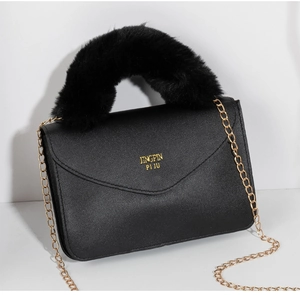 Detail of black faux leather mini square bag featuring gold chain and faux fur handle