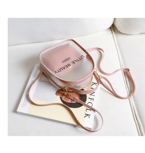 Detail of pink transparent PVC crossbody bag with Little Beauty print on white sofa
