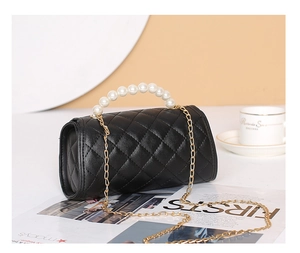 Detail of black quilted leather cylinder bag with pearl handle and gold chain strap