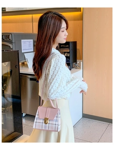 Detail of pink plaid crossbody bag with gold twist lock on a casual outfit