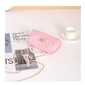 Detail of pink quilted cylindrical bag with pearl handle and golden twist lock
