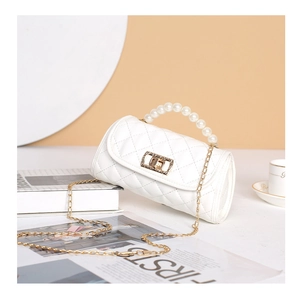 Detailed view of the elegant pearl handle and golden chain on a white quilted bag