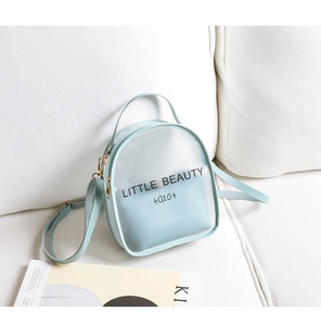 Close-up of light blue frosted mini bag with Little Beauty text on white sofa