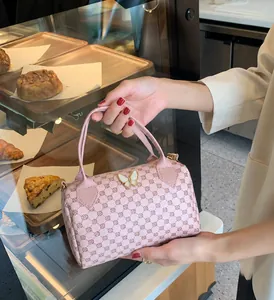 Close-up of pink Boston bag with monogram pattern and a decorative butterfly clasp