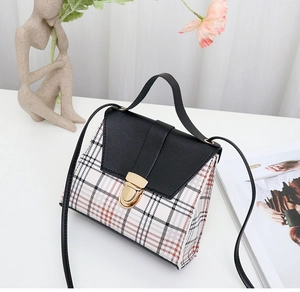 Detailed view of plaid handbag with black leather flap and golden twist-lock closure