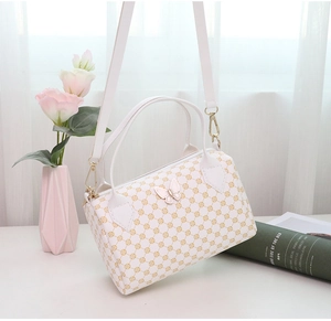 White cylinder Boston bag with gold geometric patterns and butterfly buckle detail