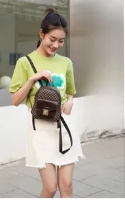 Outdoor view of a mini backpack with brown checkered pattern and metal clasp closure