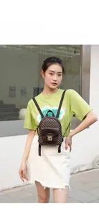 Front view of a model wearing a small brown floral pattern backpack with leather flap