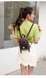 Detail of checkered mini backpack showing golden metal buckle and brown leather flap