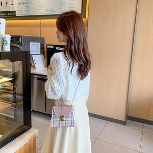 Pink and plaid crossbody mini bag with gold buckle shown in a cafe setting