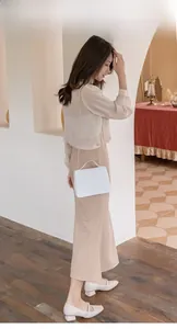 Weiße geprägte Handtasche mit goldener Kette am Model in einem eleganten Outfit