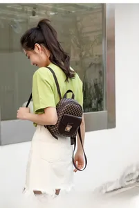 Detail shot of a brown checkered mini backpack with gold clasp and adjustable straps