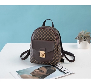 Detail of vintage mini backpack with gold lock and polka dot pattern on white surface