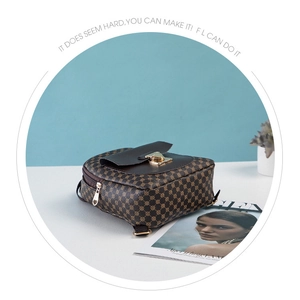 Detail of small dark brown printed backpack with golden buckle and geometric patterns