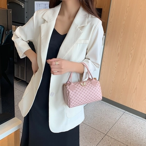 Pink monogram Boston handbag with golden butterfly detail held by a model in white blazer