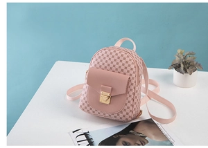 Detailed close-up of pink mini backpack with heart-shaped gold buckle on a white table