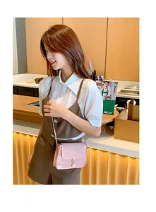 Détail d'un petit sac carré rose clair à motif crocodile avec fermoir pendentif perle