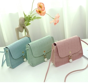 Trois mini sacs carrés à effet croco aux tons pastel avec pendentif perle sur fond blanc