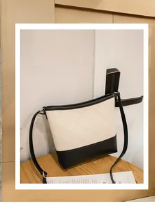 Détail d'un sac hobo contrasté en cuir matelassé beige et bordures noires sur bois