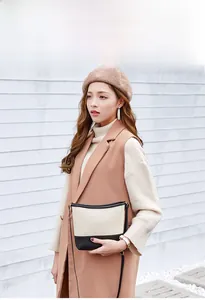 Détail d'un sac seau bicolore avec matelassage porté par un mannequin élégant