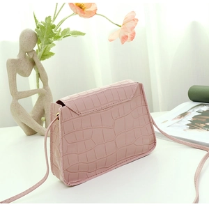 Gros plan d'un sac carré rose en similicuir avec motif crocodile et fine bandoulière