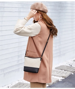 Détail du sac seau bandoulière avec texture à losanges beige et base noire élégante