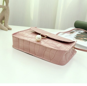 Détail du petit sac bandoulière rose gaufré croco avec anneau doré et perle décorative