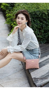 Détail d'un sac bandoulière rose matelassé avec une large sangle textile noire décorative