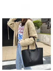 Outdoor street shot of a large black lychee texture leather tote bag with tassel detail